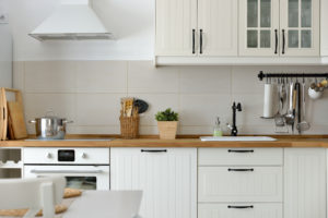 Kitchen with white cupboards, wood block counter and black hardware